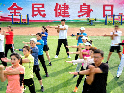 全民健身日集体热身运动场景 - 参与者在教练带领下进行拉伸
