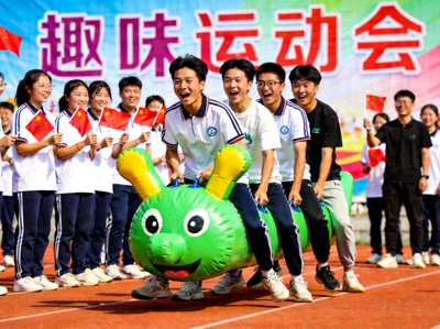 校园趣味运动会 - 学生们参与毛毛虫竞速等趣味团体游戏，欢声笑语