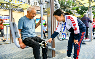 社会体育指导员在社区为居民进行健身指导 - 指导老人使用器械